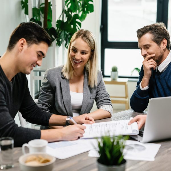 Young happy couple signing an agreement with real estate agent on a meeting in the office.